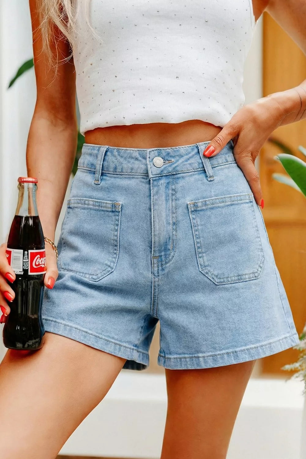 Front view of blue high-rise denim shorts with large patch pockets