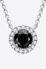 Front close-up of a round black-stone pendant with a clear-stone halo