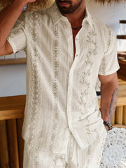 Detail view of cream shirt's embroidered pattern and short sleeves