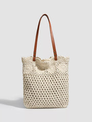 Front view of the ivory crochet tote with brown handles and a scalloped openwork top.