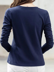 Back view of a navy long-sleeve T-shirt worn with white pants.