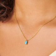 Turquoise-coloured rectangular pendant necklace worn at the neckline