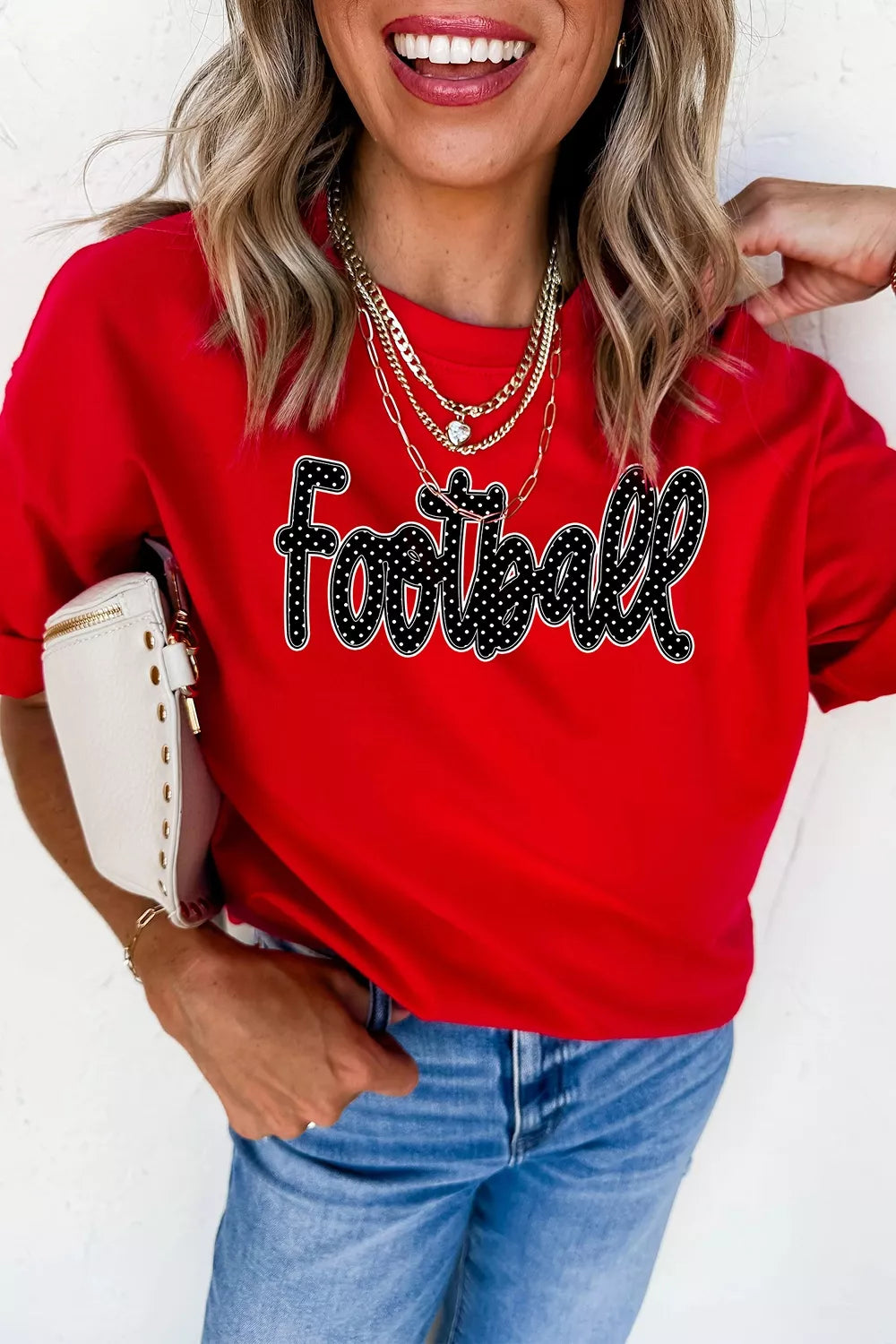 Front view of red football lettering tee styled with jeans