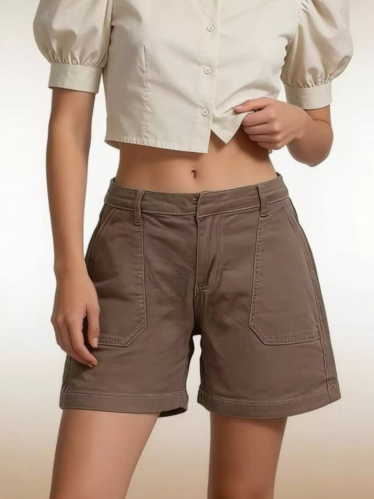 Brown pocketed denim shorts shown from the front with a beige cropped shirt