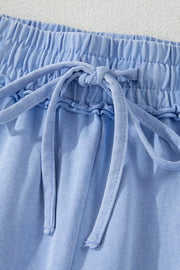 Detail of drawstring and elastic waist on light-blue shorts