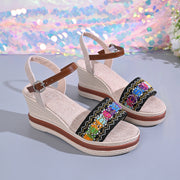 Pair of embroidered open-toe wedge sandals with ankle buckles and textured soles