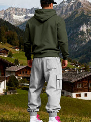 Rear view of olive hoodie and grey joggers showing the hood and back patch pocket