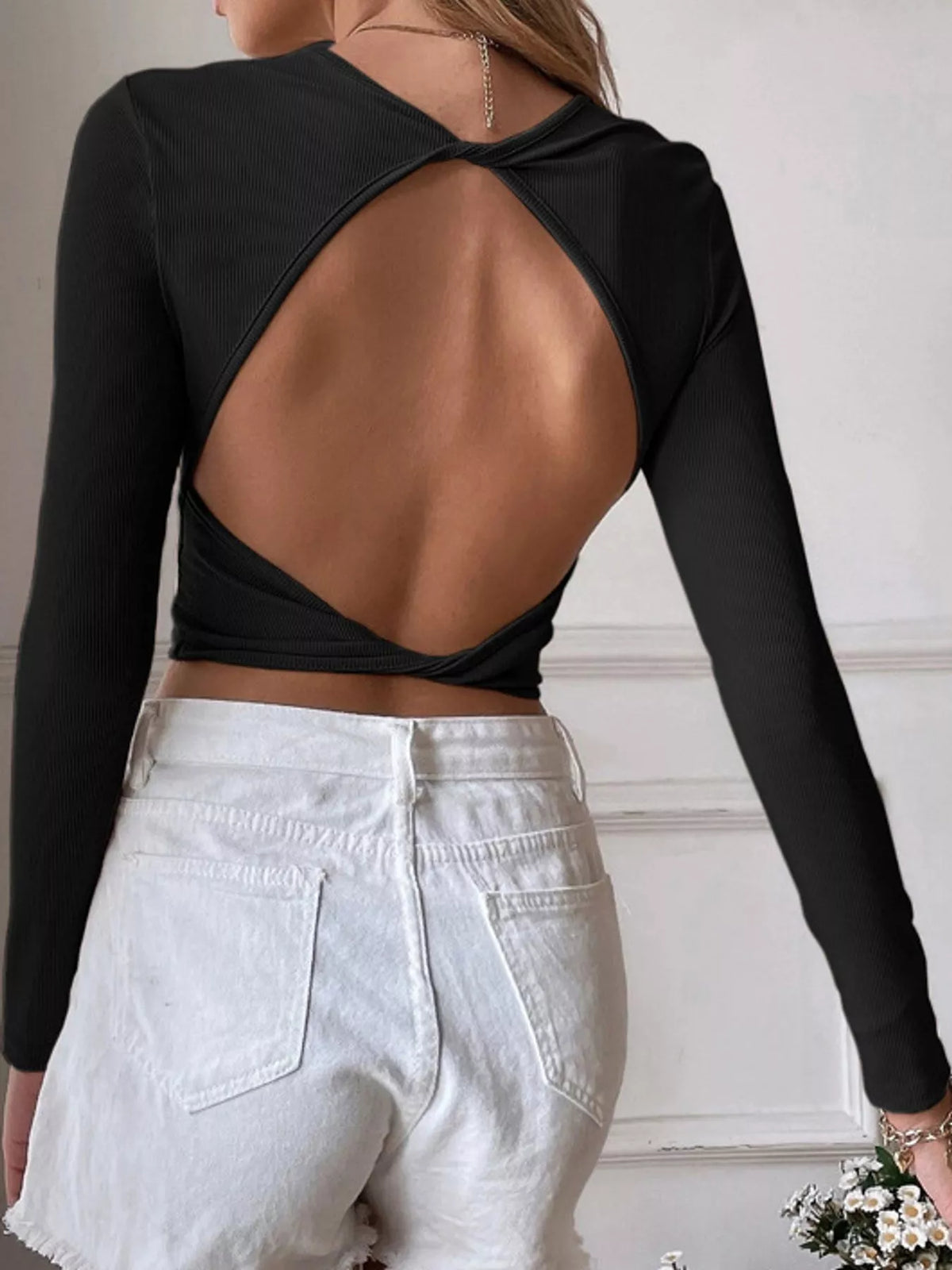 Back view of the black crop top showing its large open cutout
