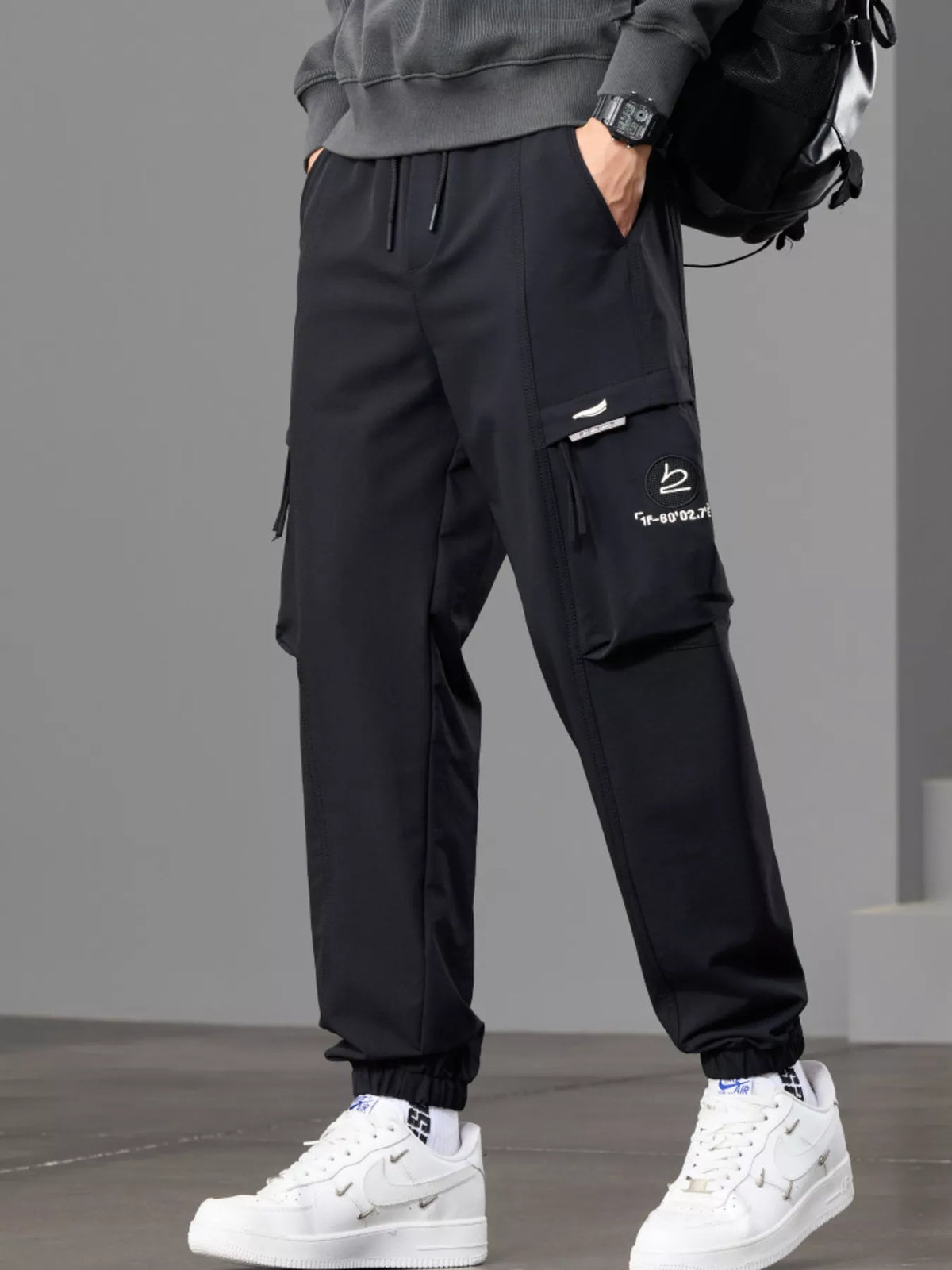 Angled front view of black joggers highlighting the large cargo pocket.