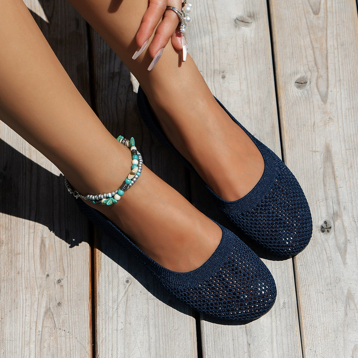 Navy mesh slip-on flats worn with jeans, angled top view