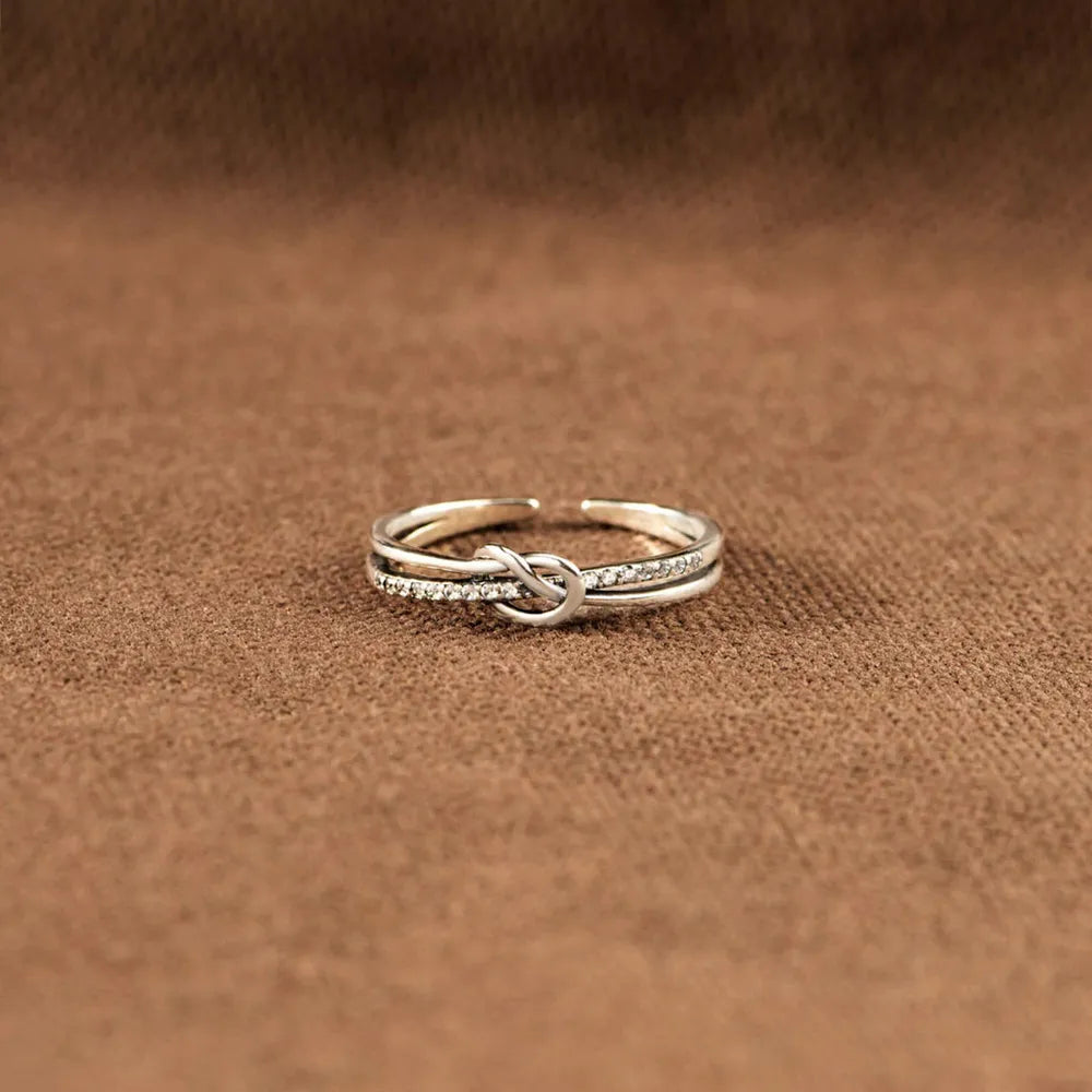 Low-angle view of the interlaced silver knot ring on a brown surface