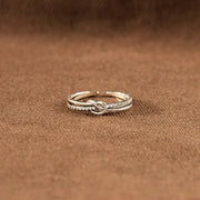 Low-angle view of the interlaced silver knot ring on a brown surface
