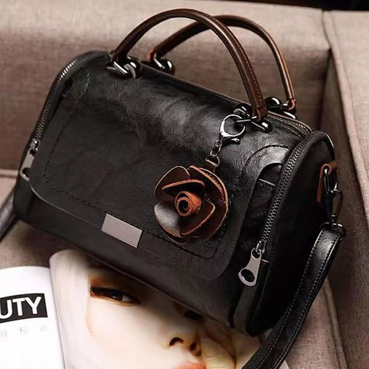 Black flap crossbody bag with brown flower ornament, viewed from the back and side