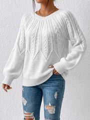 White cable-knit sweater worn with distressed jeans, front view
