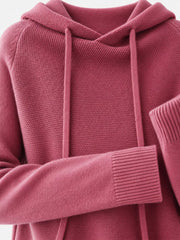Dusty pink sweater close-up showing the hood opening, drawstrings and ribbed cuff.