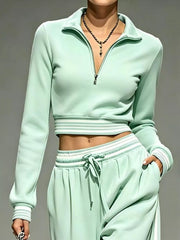 Close-up of mint cropped half-zip top with striped cuffs and waistband