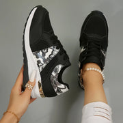 Black floral-panel sneaker held up to show the side and sole