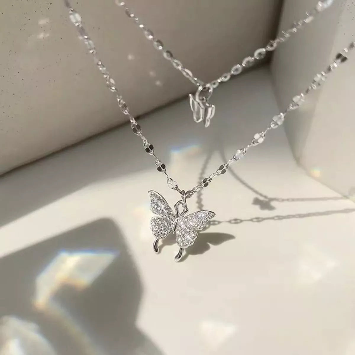 Silver-tone layered butterfly necklace laid flat with small upper charm