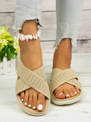 Beige woven cross-strap slide sandals with pale ridged soles, front view on feet