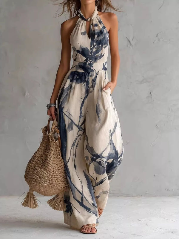 Cream halter-neck wide-leg jumpsuit with blue ink-wash floral print, full-length front view.