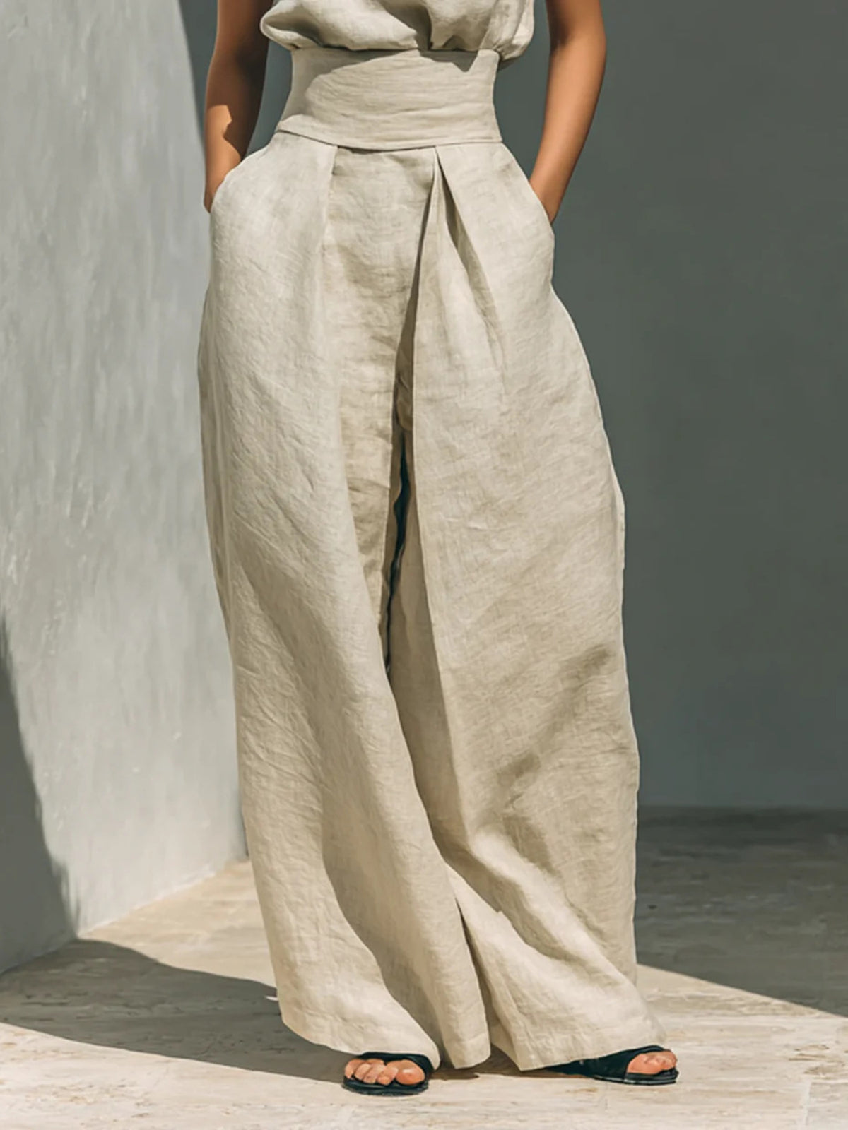 Close view of the cream trousers showing their wide legs and waist tie.