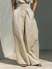 Close view of the cream trousers showing their wide legs and waist tie.