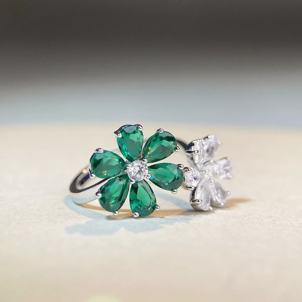 Angled close view of the green and clear flower motifs on a silver-tone ring