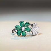 Angled close view of the green and clear flower motifs on a silver-tone ring
