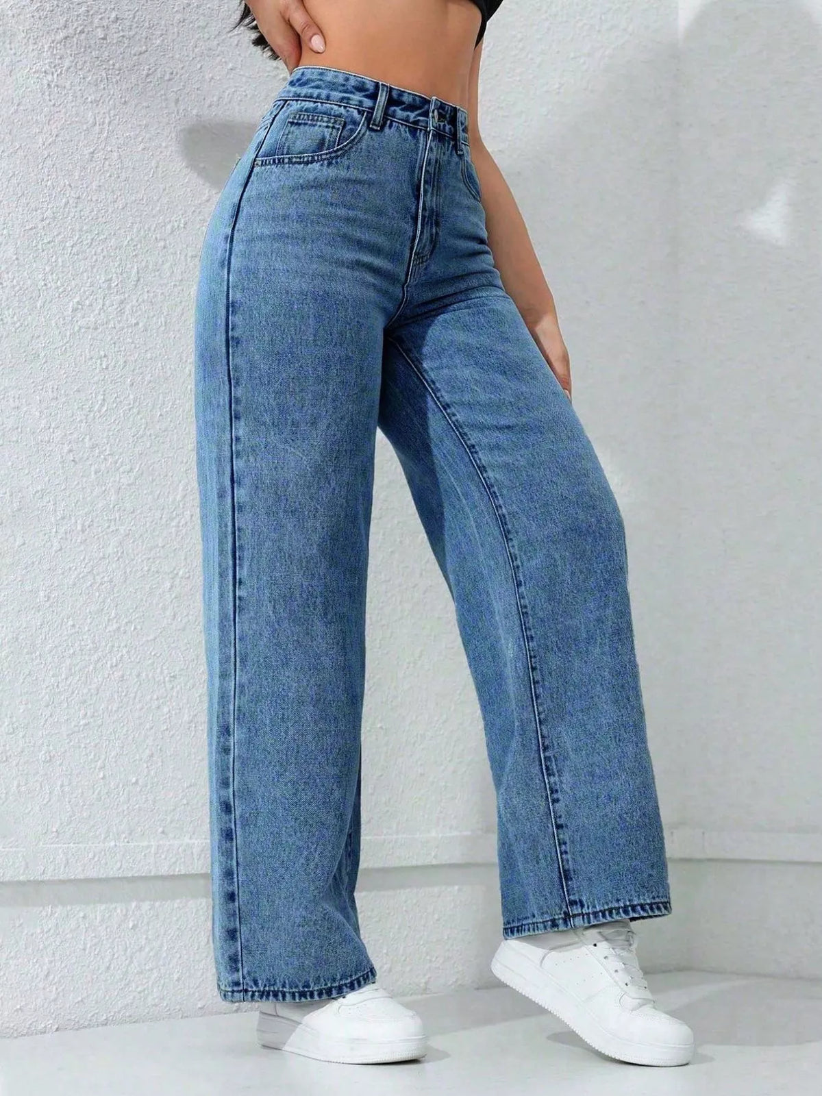 Three-quarter front view of blue wide-leg jeans with one foot stepped forward