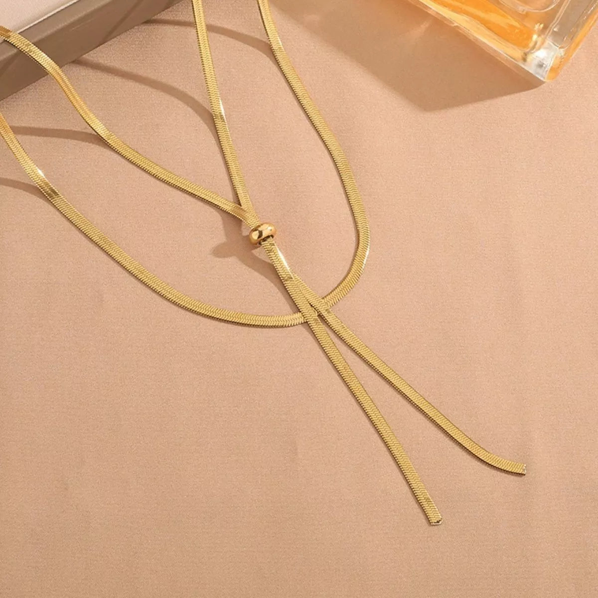 Close-up of the gold snake-chain Y necklace slider and two hanging ends