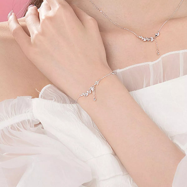 Silver leaf bracelet worn on the wrist beside a sheer sleeve