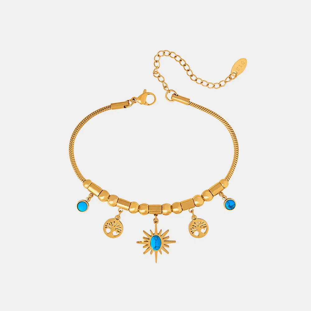 Full view of gold sun and charm bracelet on white background