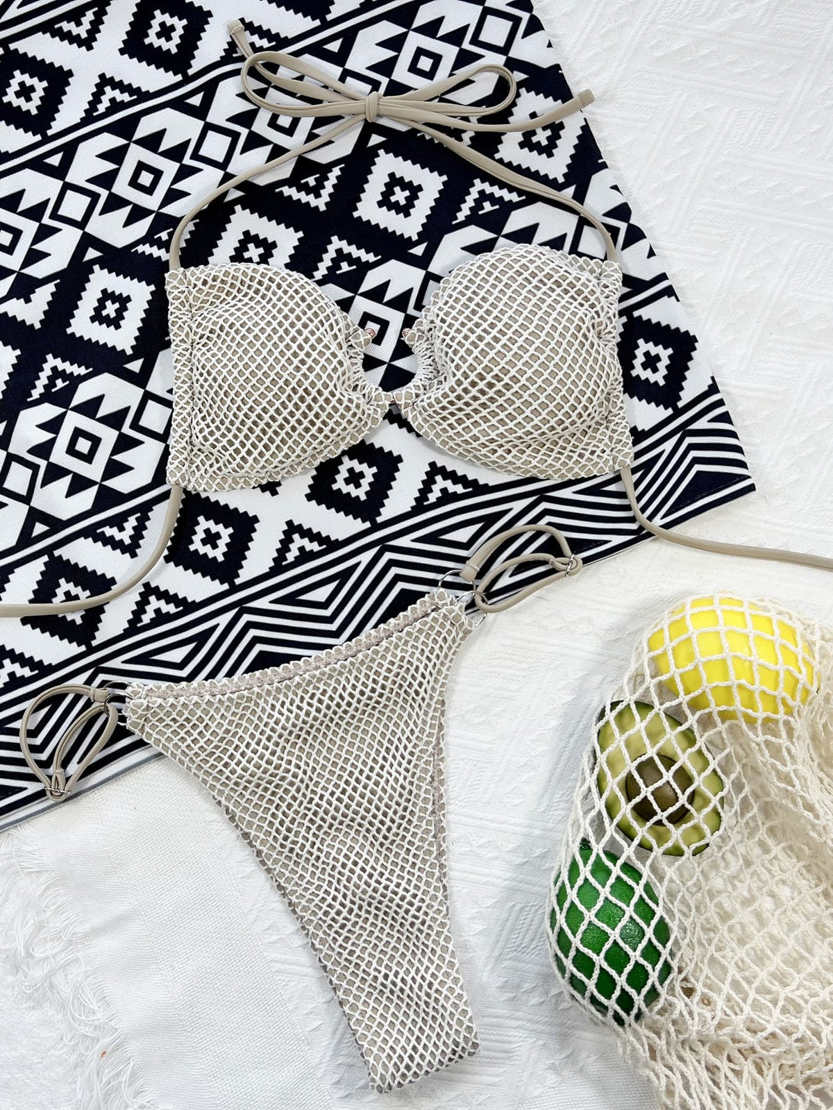 Cream fishnet bikini top and matching tie-side bottoms laid flat on a patterned cloth