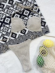 Cream fishnet bikini top and matching tie-side bottoms laid flat on a patterned cloth