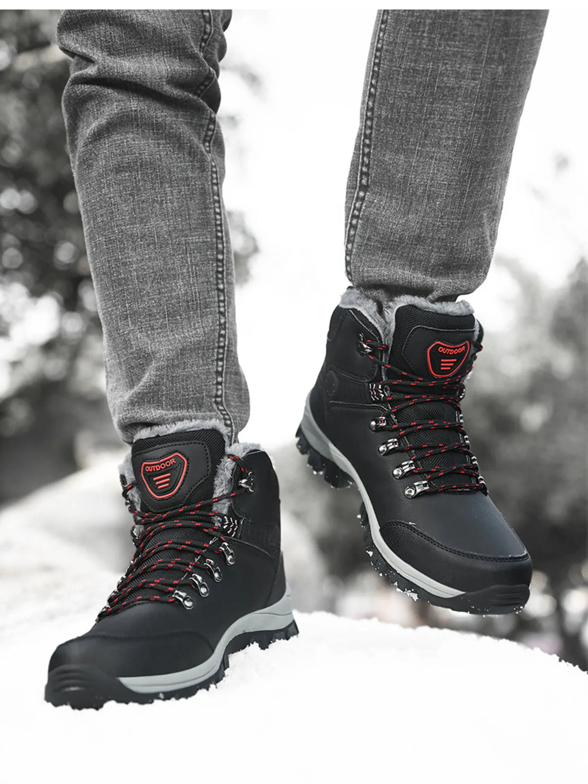 Black lace-up ankle boots with red-accented laces and grey midsoles, worn in snow