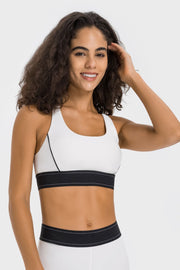 Model wearing a white sports bra with black contrast piping and hem