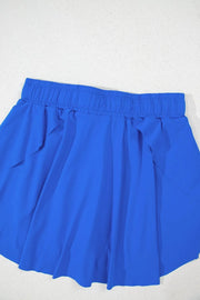 Rear view of blue skort laid flat, showing elastic waistband and skirt panels