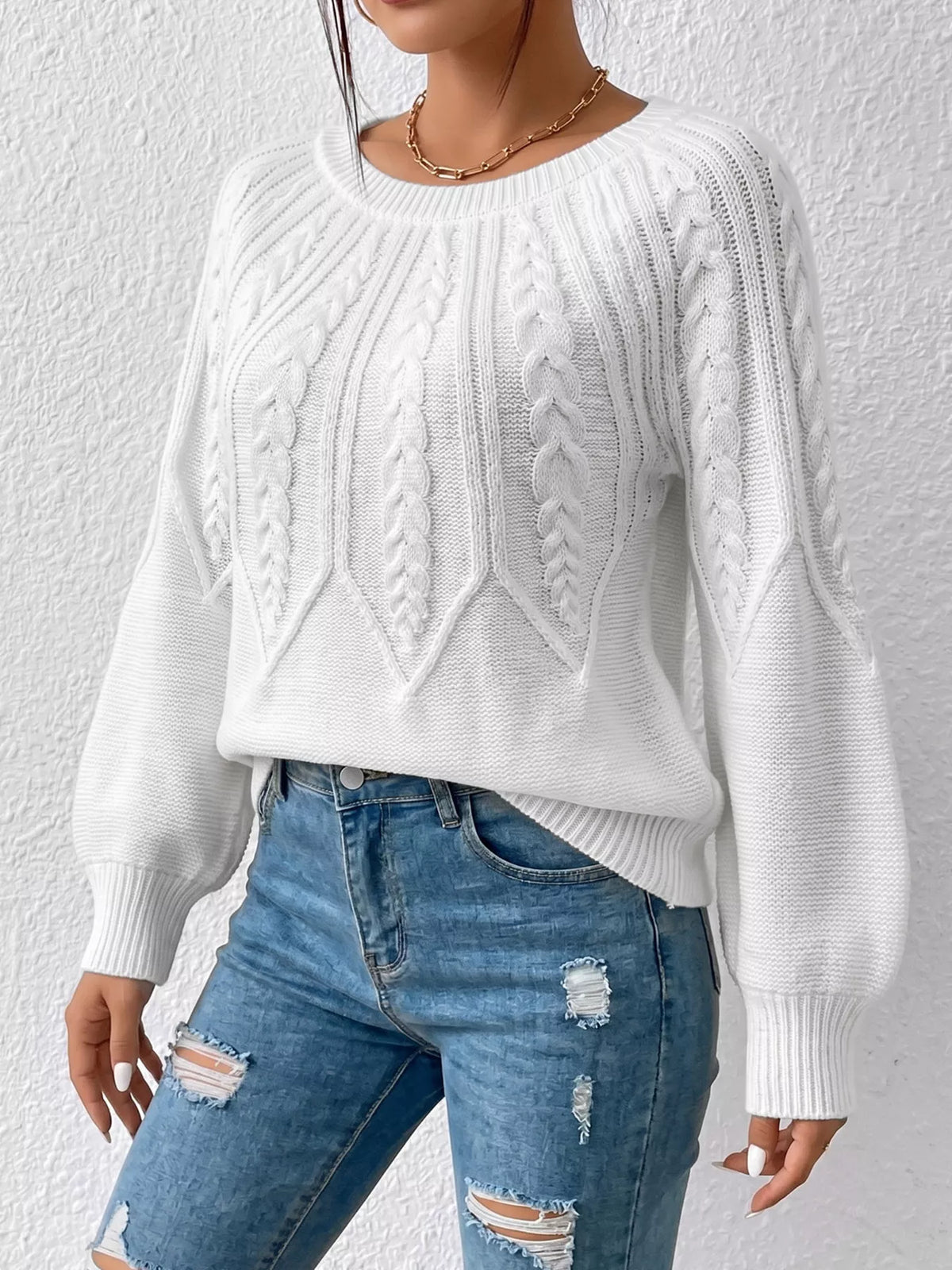 White cable-knit sweater shown from the front with sleeves relaxed