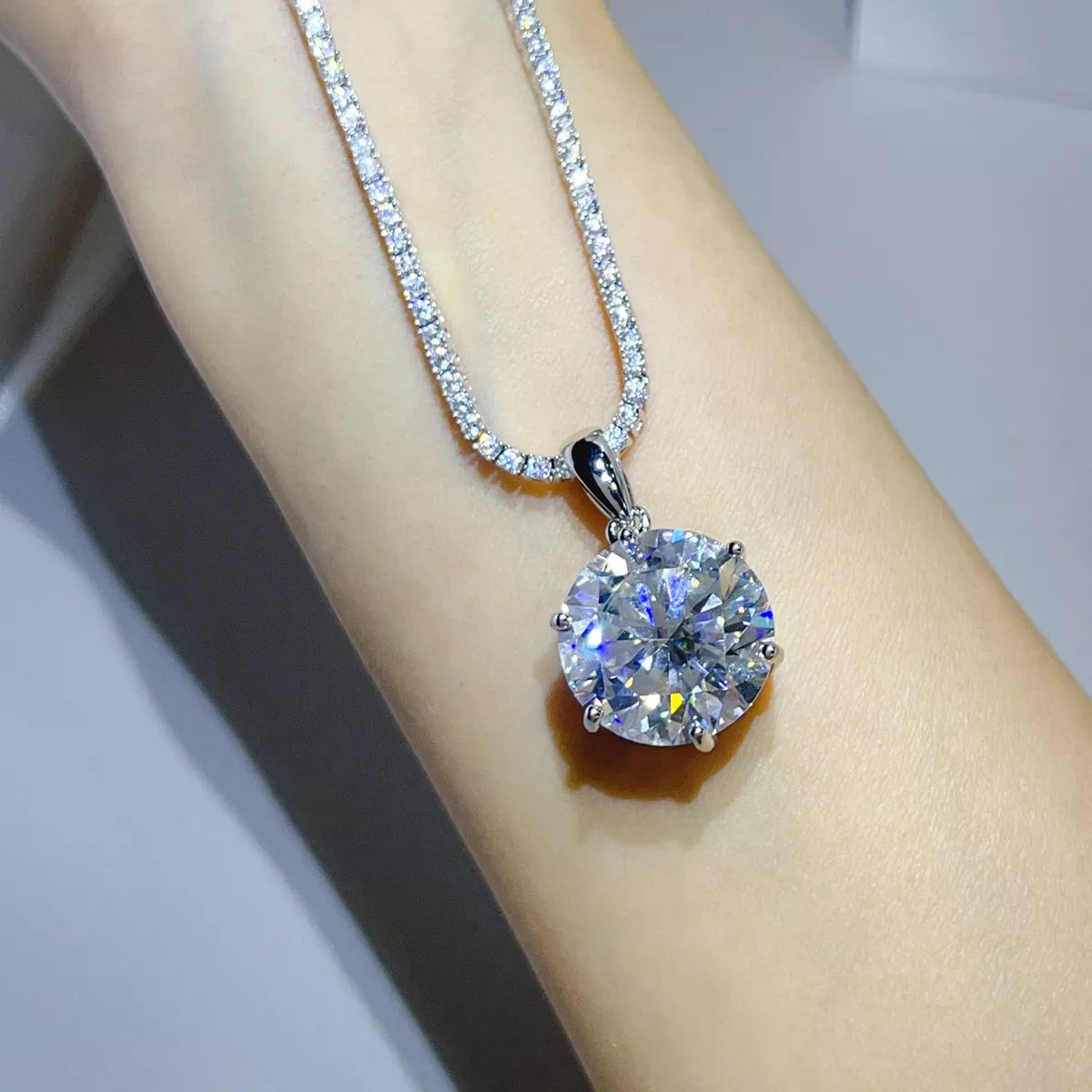 Close view of the round moissanite pendant and chain worn over an arm