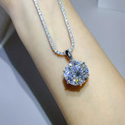 Close view of the round moissanite pendant and chain worn over an arm