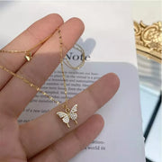 Gold-tone butterfly pendant held in a hand beside product card