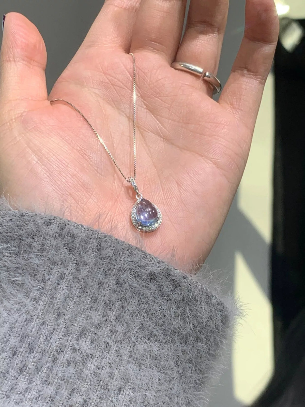 Close view of blue teardrop pendant resting against a hand