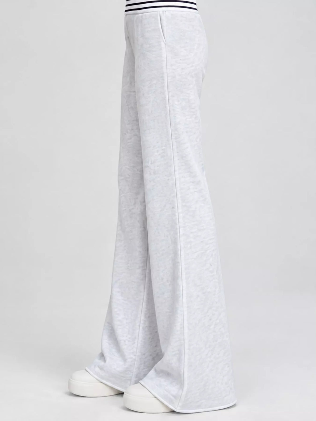 Side view of light grey high-waisted flare pants with white shoes