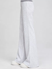 Side view of light grey high-waisted flare pants with white shoes