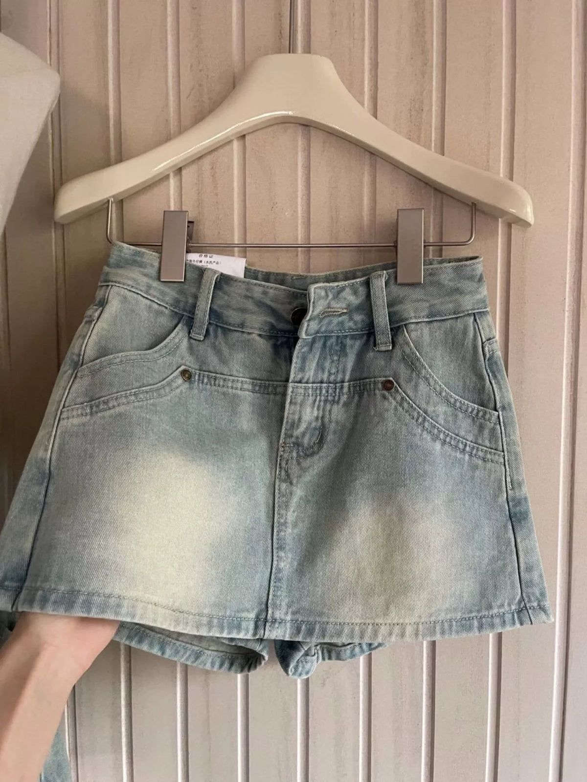 Front view of light-wash high-waisted denim shorts on hanger