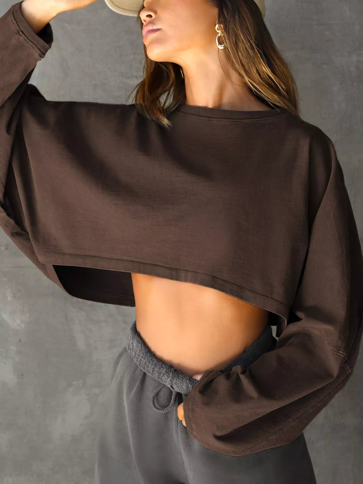 Front view of a dark brown cropped sweatshirt with long sleeves, worn with dark gray pants.