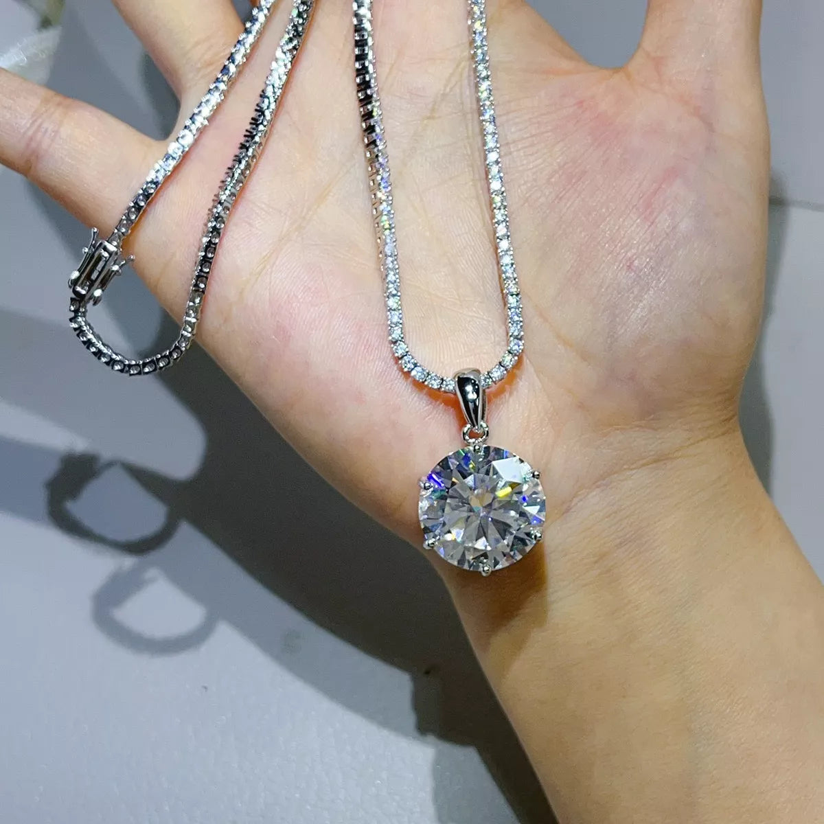 Close view of the round moissanite pendant necklace resting on a hand