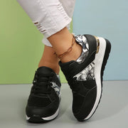 Black floral-panel sneakers worn, showing the raised wedge sole