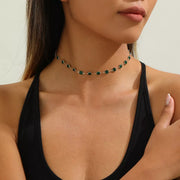Dark green rhinestone choker necklace with gold-tone settings, worn at the neck
