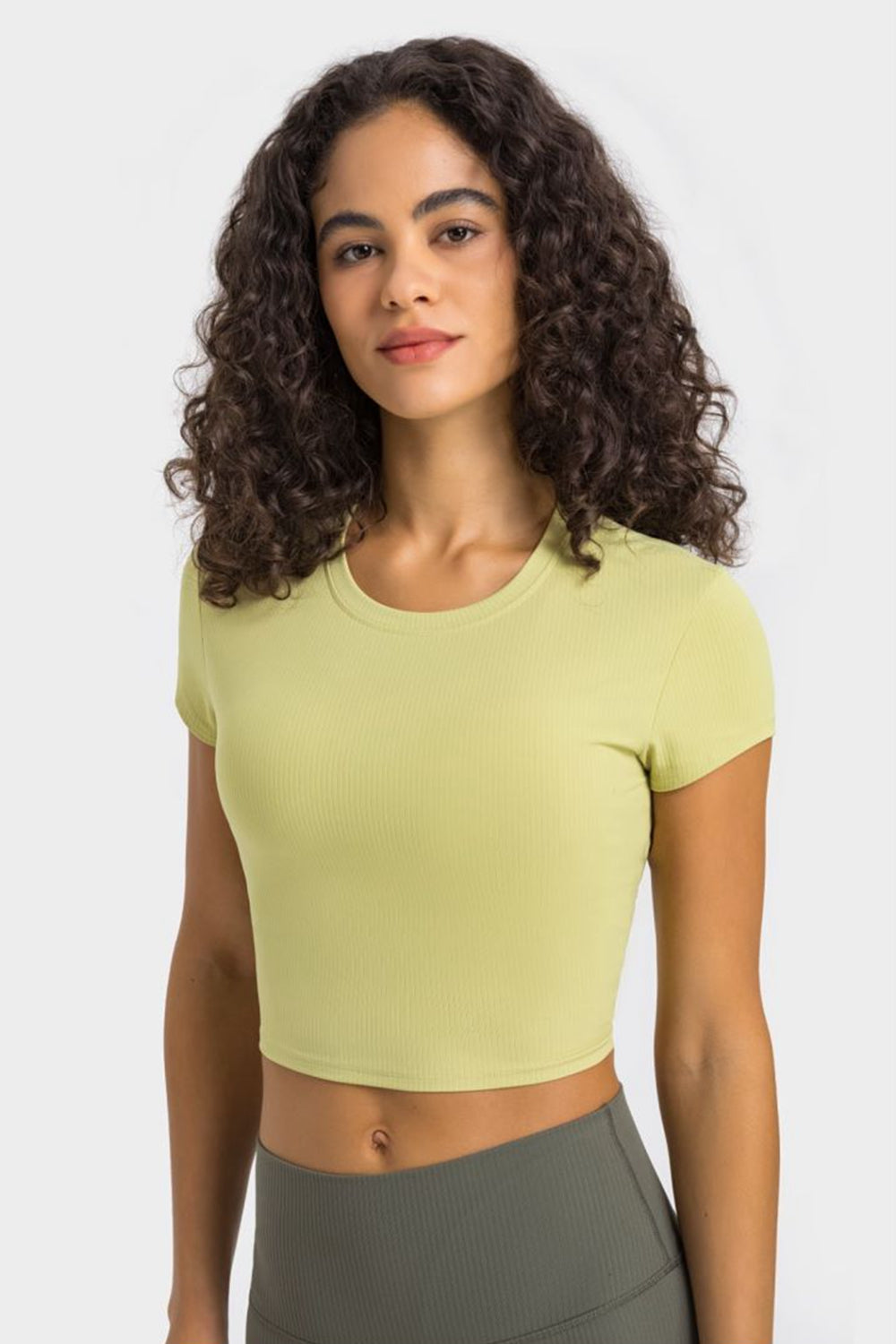 Model wearing a pale yellow cropped sports T-shirt, front view